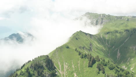 Blick-Aus-Der-Vogelperspektive-Auf-Weiße-Wolken,-Die-Mit-Grünen-Berggipfeln-Kollidieren