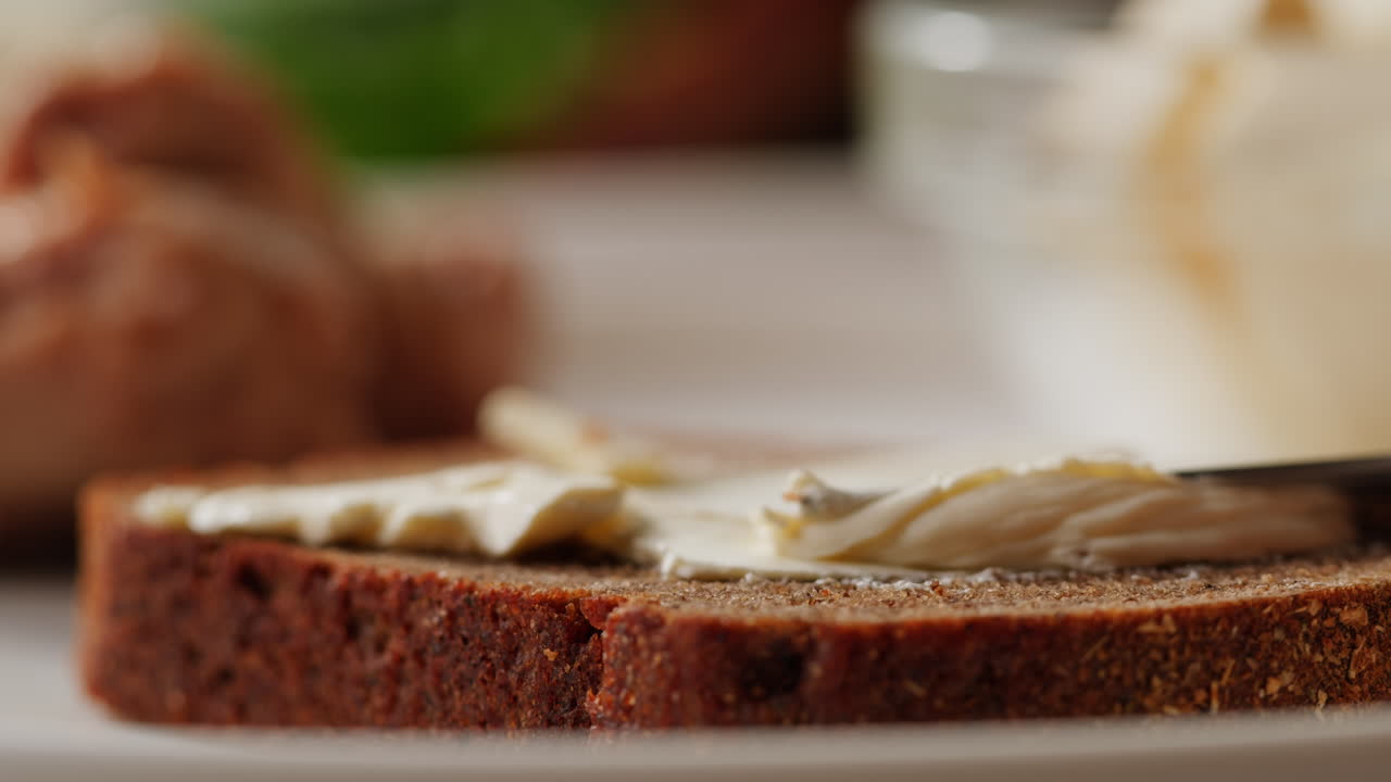 Young woman spreading nut butter onto toast in kitchen, closeup. High quality 4k footage