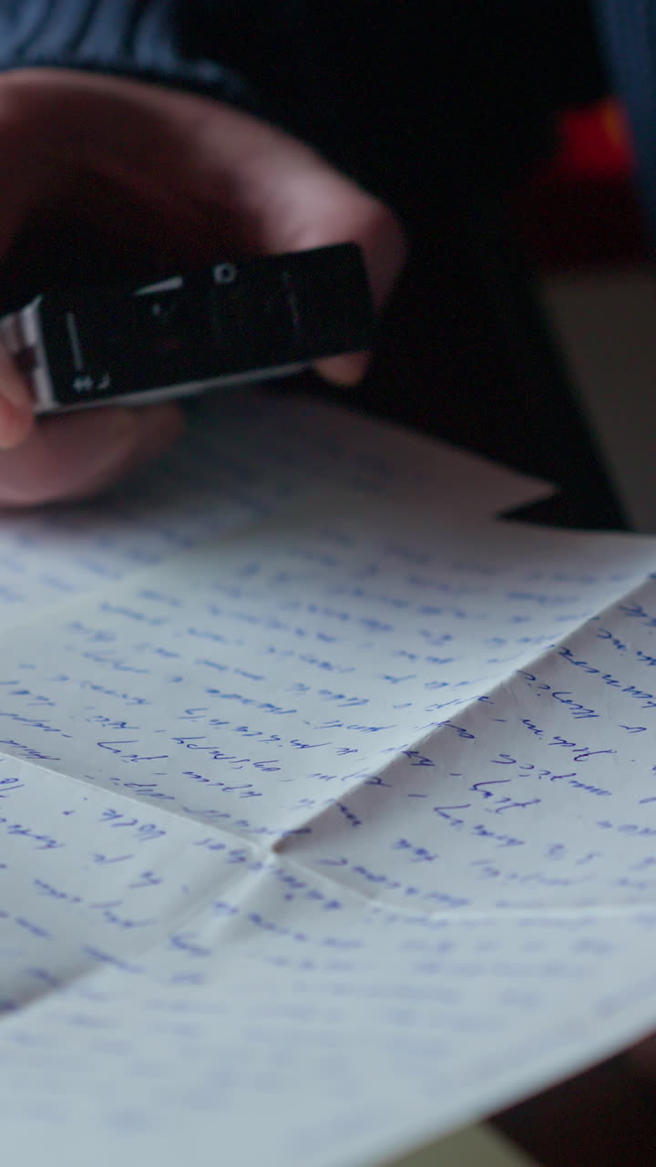 Vertical close-up of handwritten letter while voice recording plays on analogue dictaphone. Useful for storytelling, journalism visuals, research and archive themes