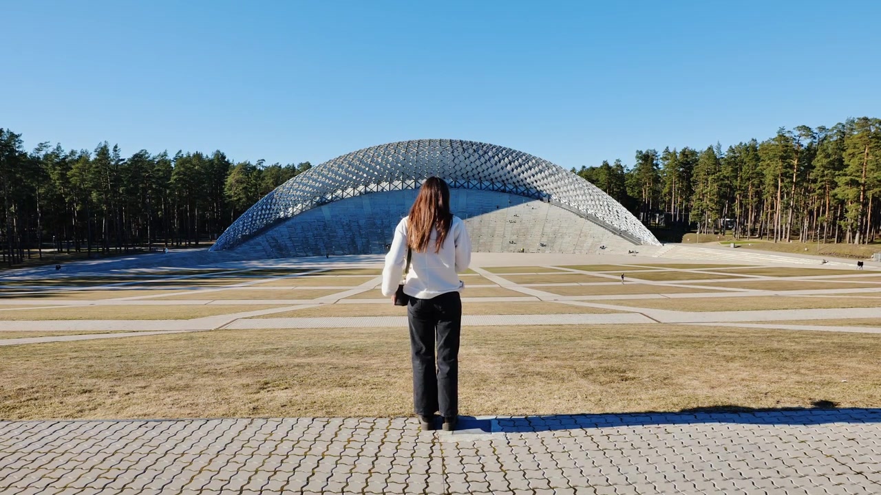 Mujer revisa su teléfono junto al Gran Quiosco de Música de Mezaparks en Riga, filmado en cámara lenta
