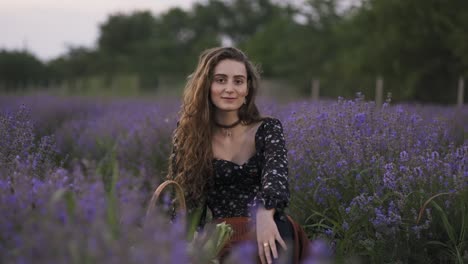 lovely young woman wearing stylish dress and sitting in purple lavender field