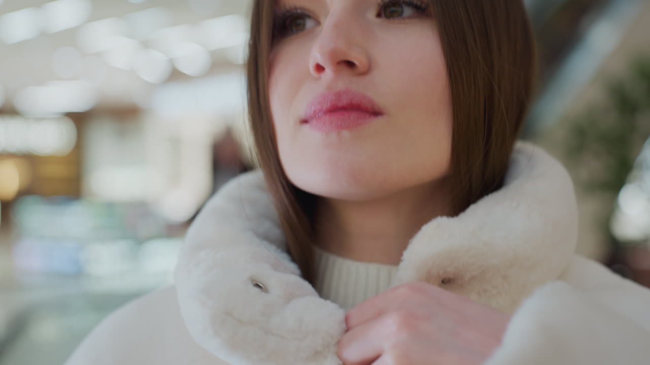 Close-up of woman hands zipping up a soft, fluffy winter jacket with a blurred background featuring warm bokeh lights, cozy outerwear fashion for cold weather in a stylish seasonal setting
