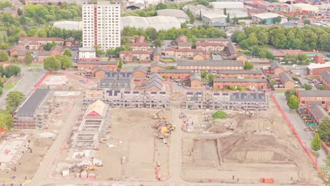 aerial view of an active, large-scale housing construction site in salford with cleared foundations and equipment, adjacent to residential towers—likely part of longshaw drive or ordsall regeneration