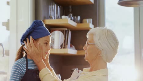 Grandma-adjusting-little-girl-chef-cap-and-kissing-her-on-forehead-4K-4k