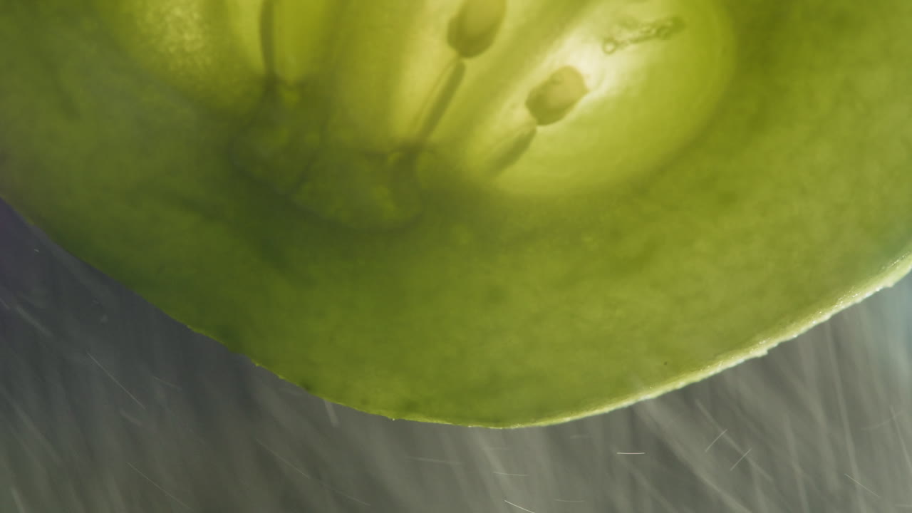 Close Up of Green Tomato Slice with Falling Water Drops