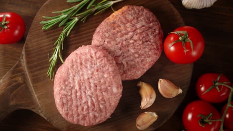 raw burger with garlic, rosemary and tomatoes rotates.