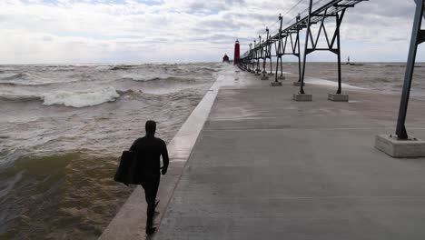 walking behind a surfer on the grand haven, michigan pier on lake michigan