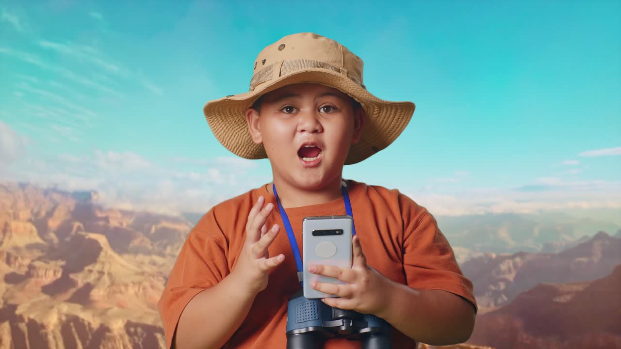 Asian Boy With A Hat And Binoculars Looking At Smartphone Then Saying Wow. Boy Researcher Examines Something While Traveling At The Top Of Mountain, Travel Tourism Adventure Concept, Close Up