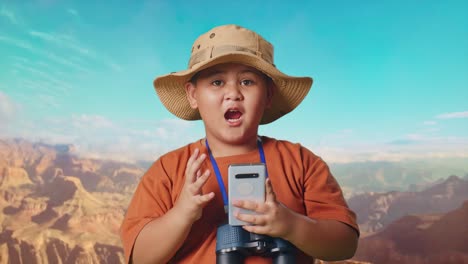asian boy with a hat and binoculars looking at smartphone then saying wow. boy researcher examines something while traveling at the top of mountain, travel tourism adventure concept, close up