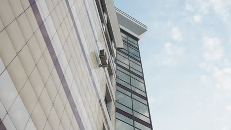 close side view of a modern city building with an air conditioner unit mounted on the wall, having a sleek design of the building's facade and reflective glass windows