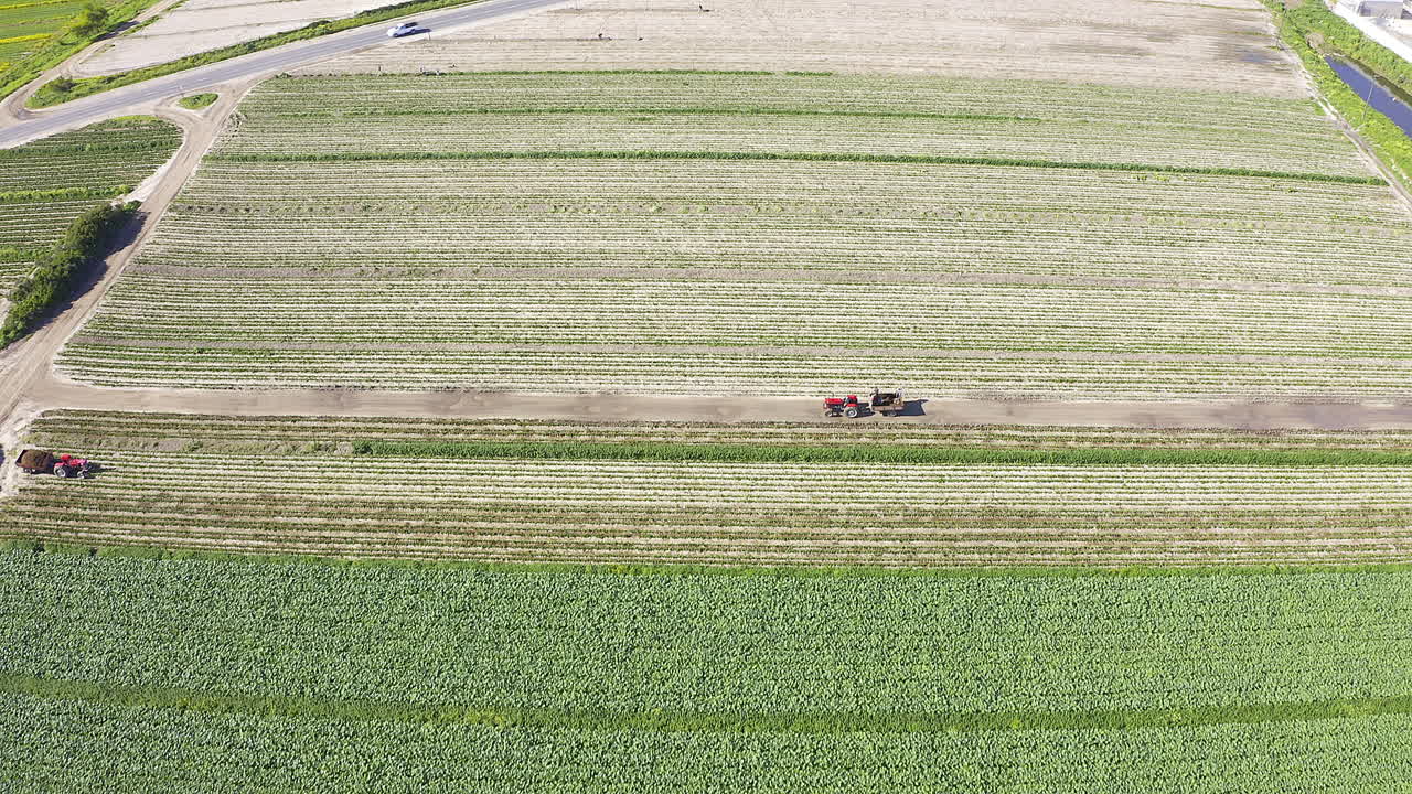 vista aérea de una granja con tractores trabajando en los campos.