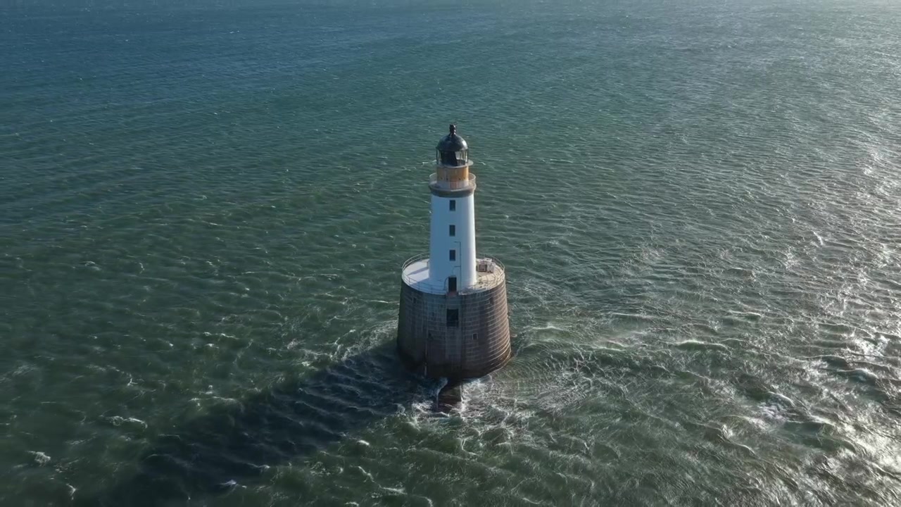 Pemandangan udara mercusuar bersejarah Rattray Head di Aberdeenshire, Skotlandia, berdiri kokoh menghadapi ombak Laut Utara yang bergejolak.