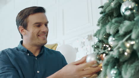 relaxed man decorating christmas tree in living room