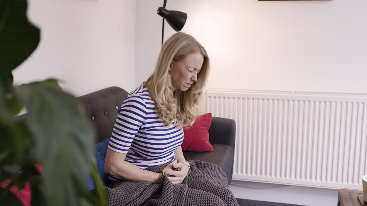 Woman experiencing stomach pain at home