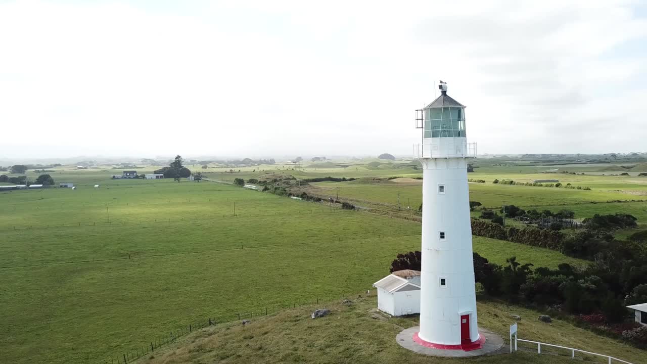 Aerial View of a White Lighthouse in a Green Field