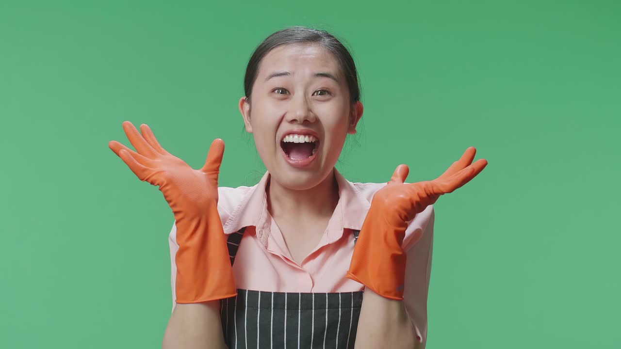 초록색 스크린 스튜디오에서 손, 손바닥, 와우 라고 말하는 제스처를 보여주고 미소 짓는 아시안 여성 집주인의 클로즈업