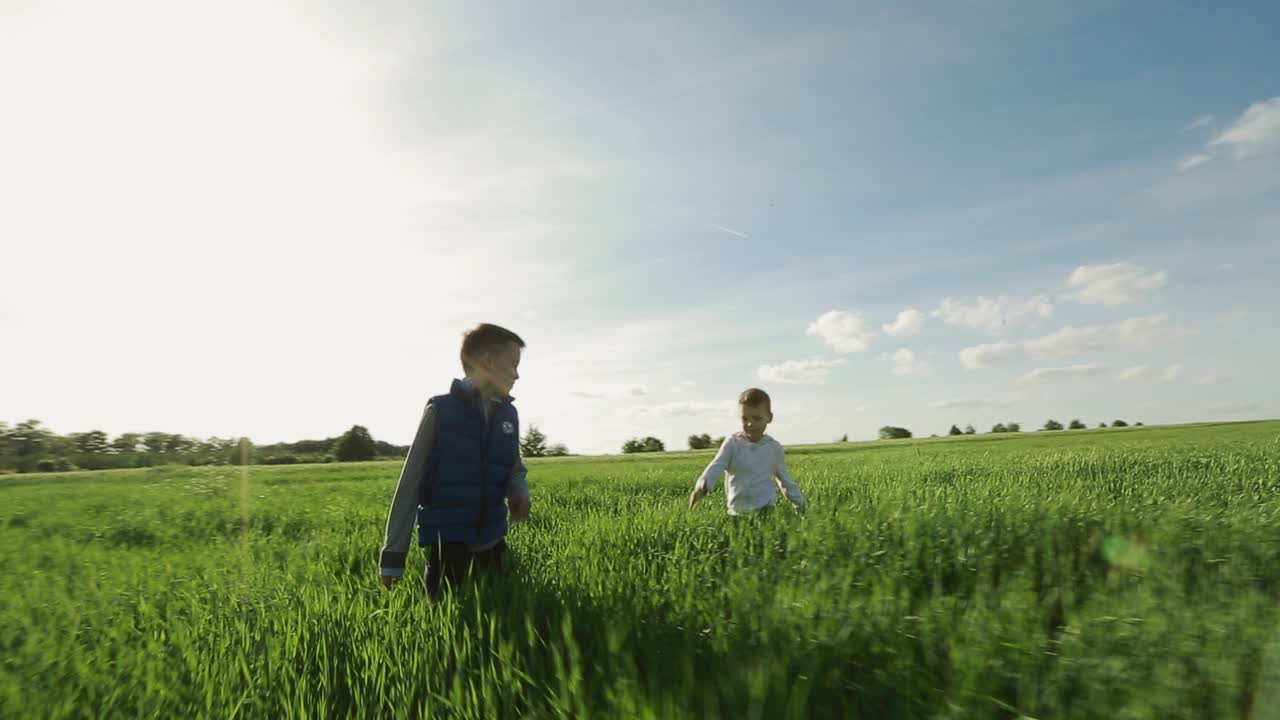 Young Boys Playing In A Field. Two happy children running in summer park