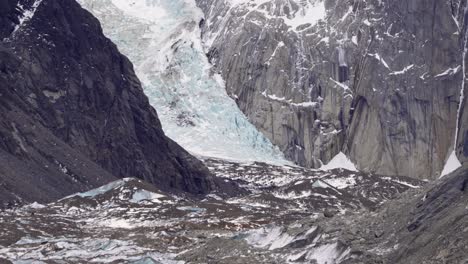 terreno montañoso cubierto de hielo con un glaciar masivo anidado entre acantilados rocosos y manchas de nieve