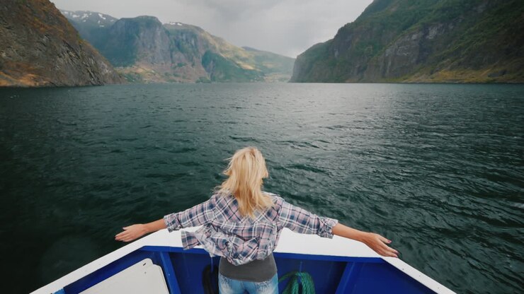 Une femme se tient à la proue du navire, naviguant sur le fjord en Norvège et appréciant le voyage.