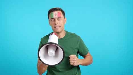 excited man with mexican flag on face using a megaphone