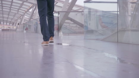 hombre elegante caminando en un pasillo ligero con paredes de vidrio