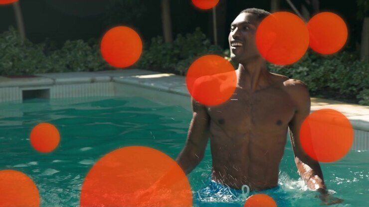 Man reaching for tossed ball, falling in pool for marketing, orange circles obscuring