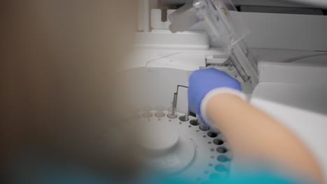 clínico insertando una muestra de orina en una centrífuga médica