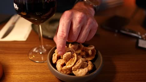 hand, die nach schweinefleisch-snacks mit wein reicht