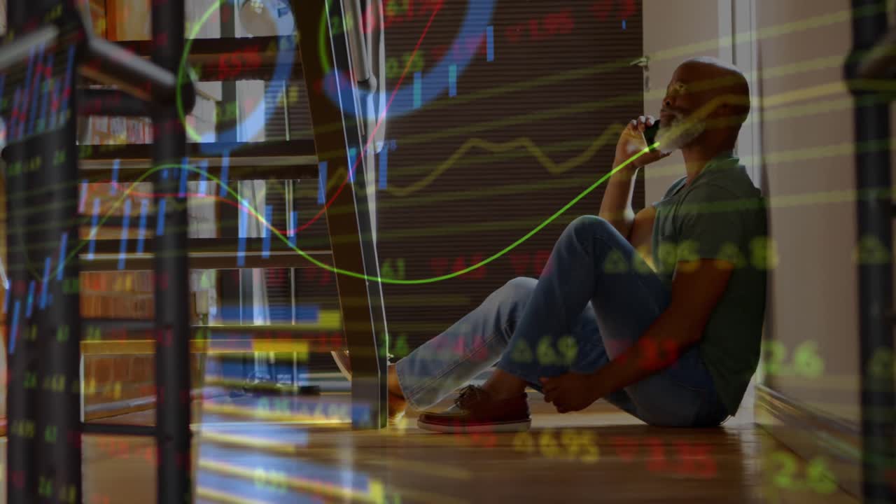 Animation of stock market data processing against african american man talking on smartphone at home