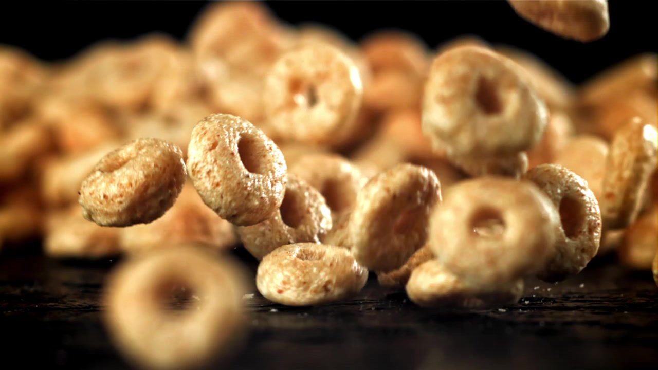 Anelli di cereali dorati che cadono in super rallentatore