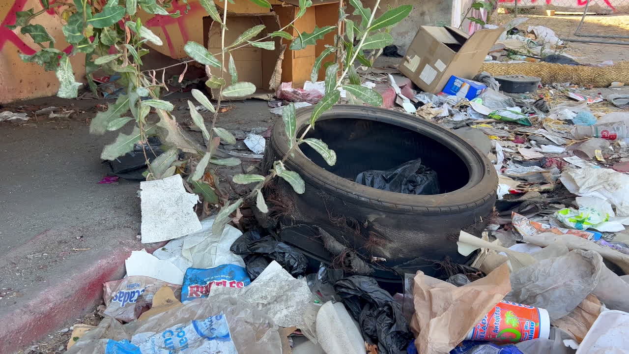 타이어와 패스트푸드 포장지 주변의 도시 보도에 놓여 있는 쓰레기 포장지 더미