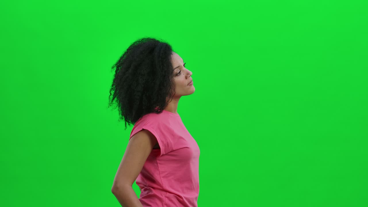Side view of young female African American considering something. Black woman with curly hair poses on green screen in the studio. Close up. Slow motion ready 59.97fps