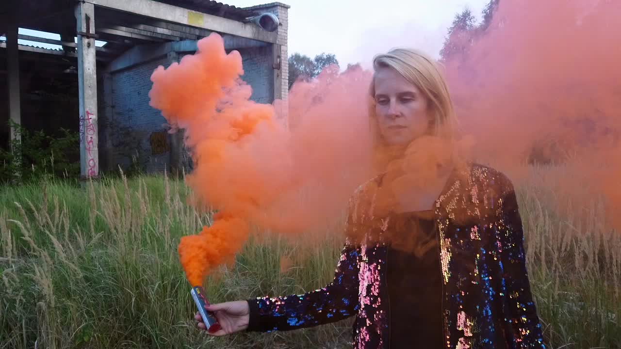 Spectacular slow motion cinematic shot of a Woman in front of a tank hall with graffiti.Colorful fog shooting. Gimbal foto video shoot on lost places in wild nature 1080, 24p by Philipp Marnitz