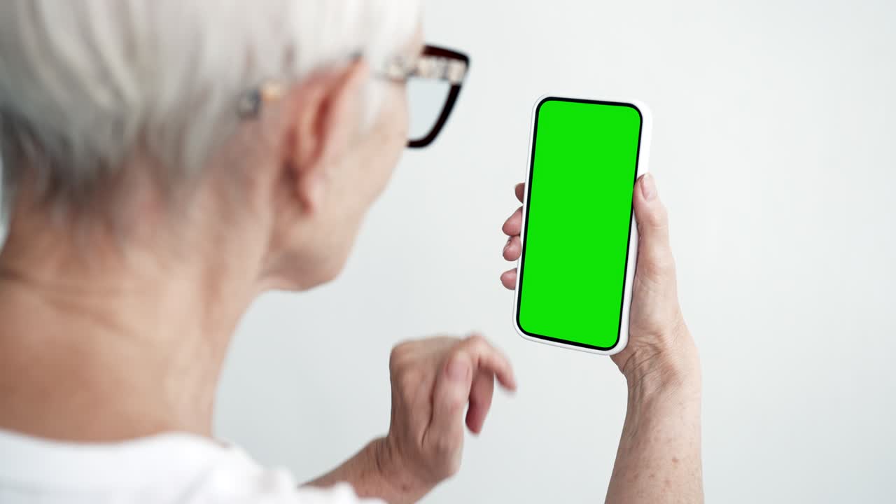 노인 터치 스크린 스마트폰 녹색 크로마 키 클로즈업 60대 여성 손에 드폰을 들고 클릭하는 모형 컨셉 시청 및 인터넷 쇼 소셜 미디어, 뉴스 읽기, 앱 전자 쇼핑 4k
