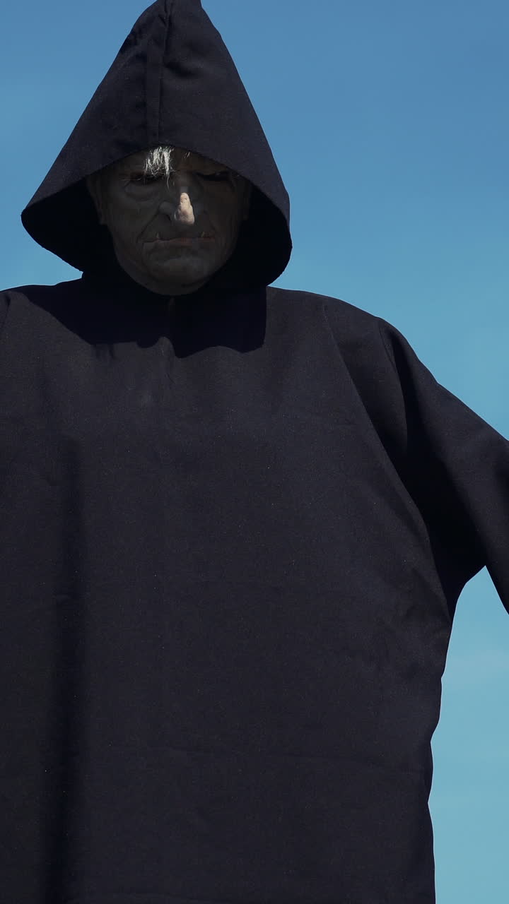 Eerie witch watches the camera. Halloween costume.. Vertical video