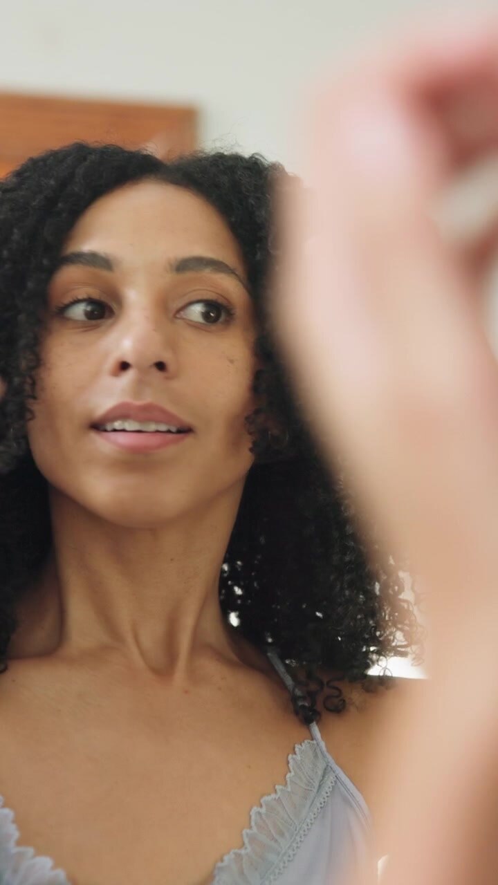 Giovane Donna che Sistema i Suoi Capelli Ricci Davanti allo Specchio