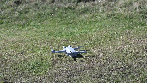 Eine-Drohne-Landet-Auf-Einem-Grasbewachsenen-Boden,-Filmausrüstung-Mit-Propellern