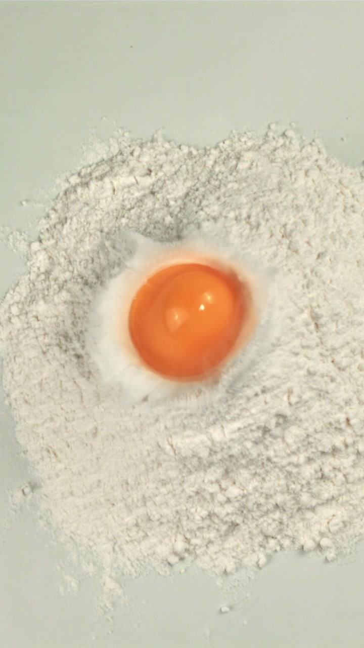 Fresh Egg Yolk Drops into White Flour in Slow Motion