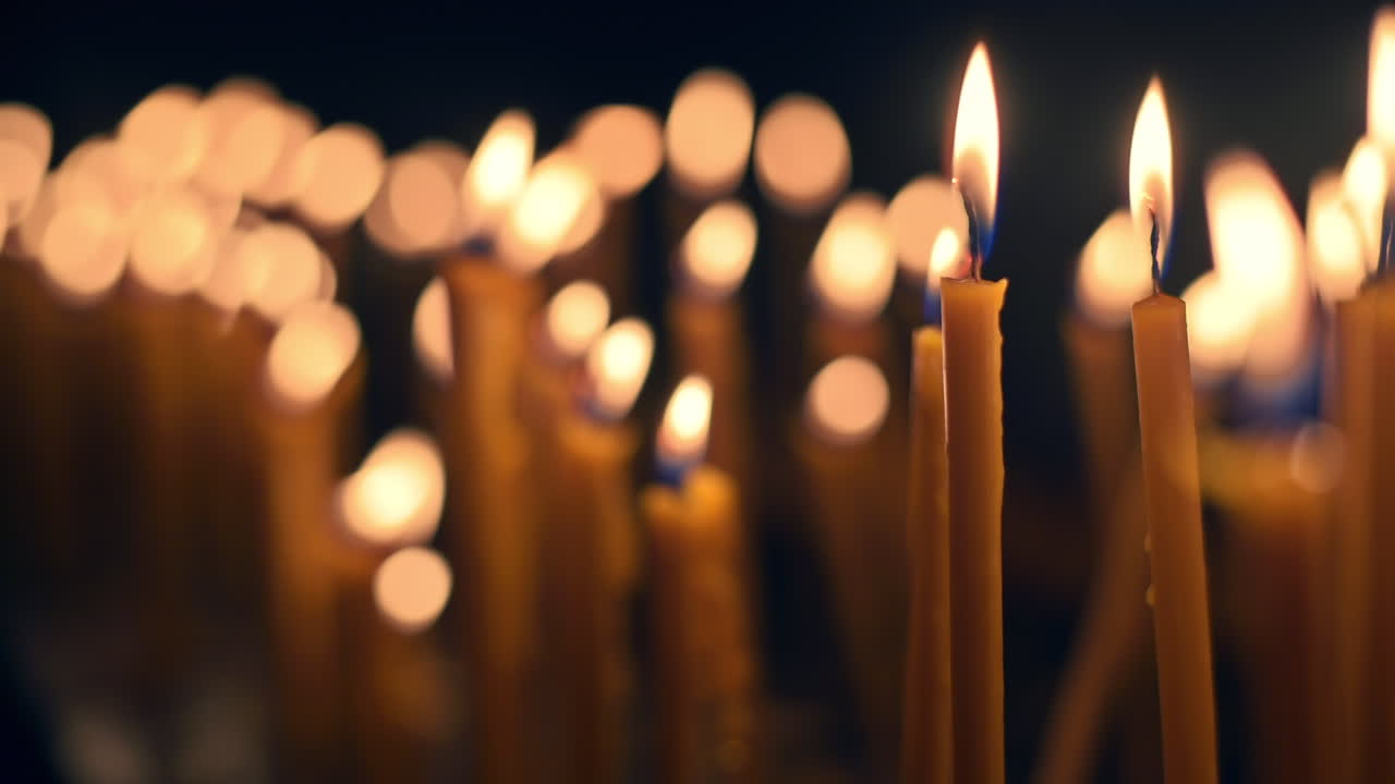Primo piano di molte candele accese con sfondo nero