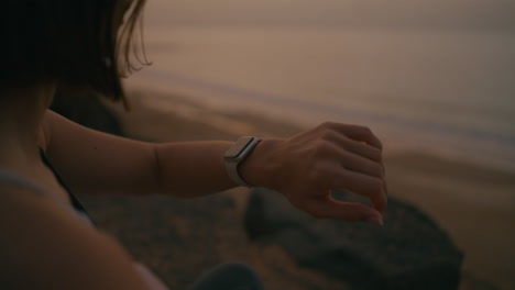 woman checking smartwatch at sunset on beach