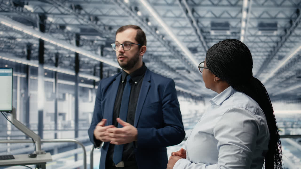 Donna e collega che monitorano linee di produzione automatizzate di semiconduttori.