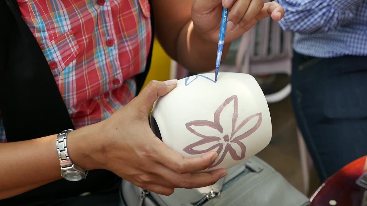 Asian Woman is painting on the clay Pottery by hand
