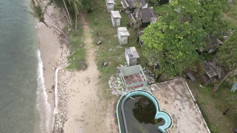 aerial-birds-eye-view-dolly-shot-of-a-abandoned-derelict-destroyed-beach-resort-from-with-broken-down-bungalows-on-a-beach-in-Thailand,-the-effects-of-covid-19