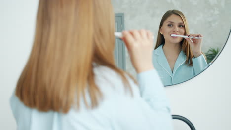 mujer cepillándose los dientes frente al espejo