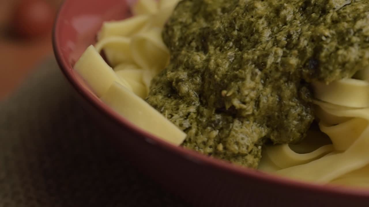 Porzione di pesto verde e tagliatelle in rotazione, ripresa macro.