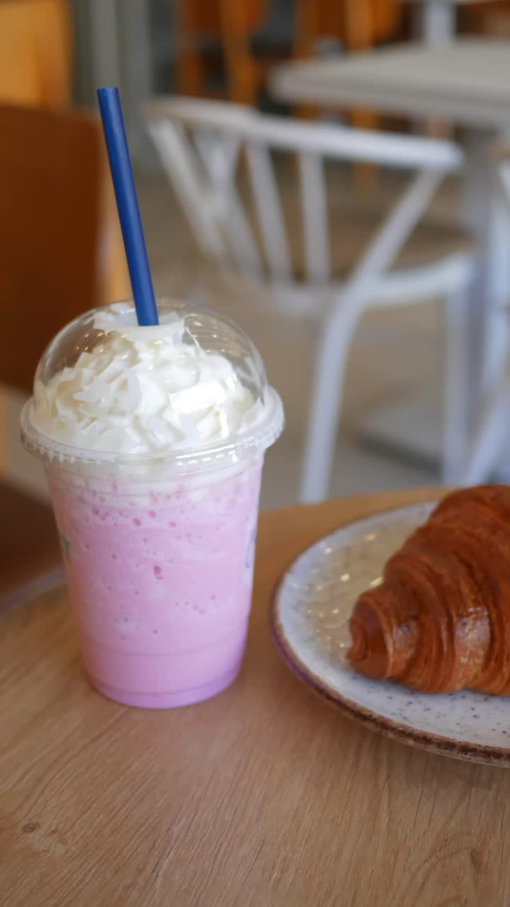 Elin Krem Şantili Pembe Bir Milkshake ve Kruvasanı Alması