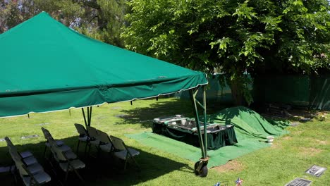 baja panorámica aérea de un sitio de la tumba listo para el entierro como la fiesta del funeral llega en el fondo en una morgue en california