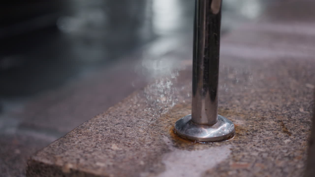 돌로 된 계단에 있는 금속 드레일의 근사한 모습, 재료의 질감을 강조하는, 부드럽고 반사적인 금속은 거칠고 날씨가 은 것과 대조된다.