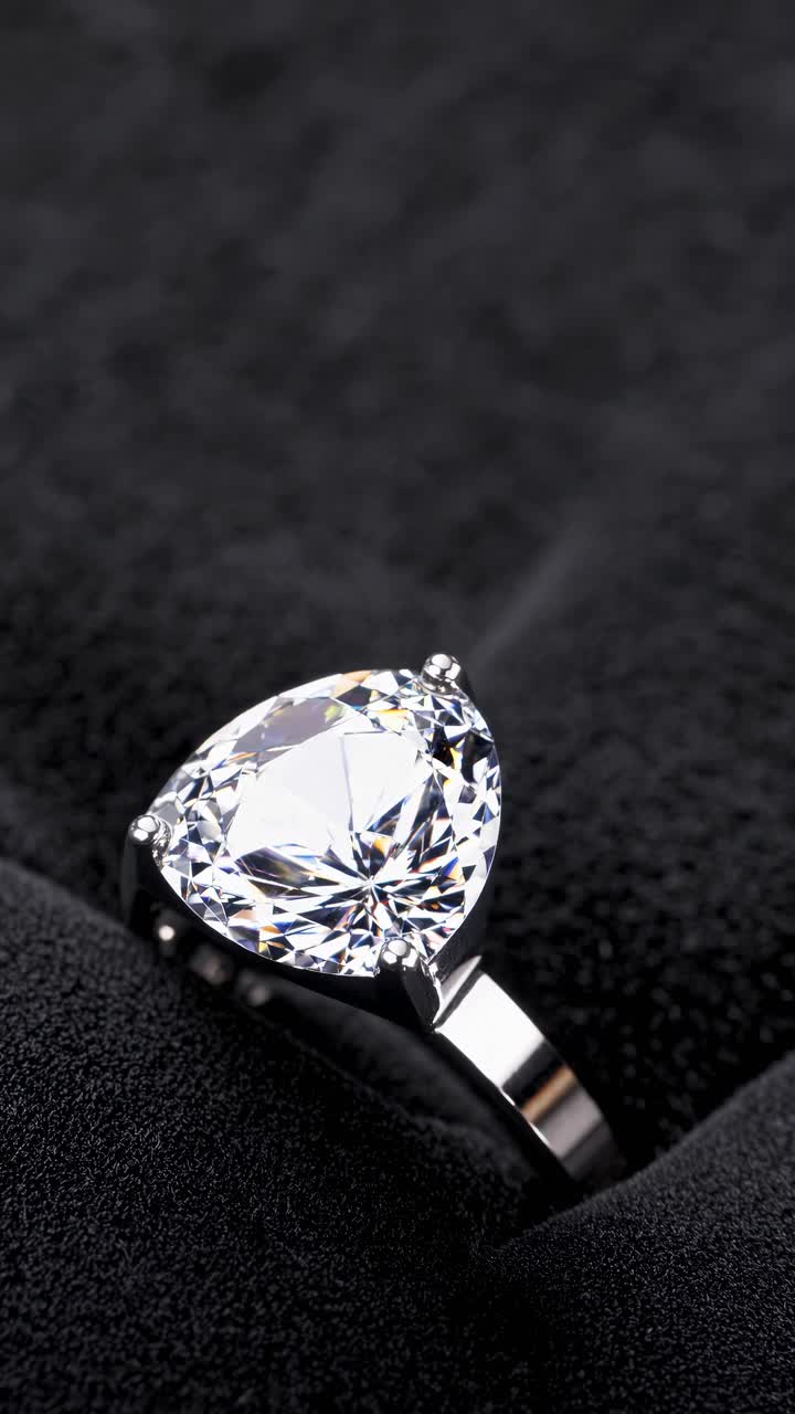 Close-up shot of a sparkling diamond ring on a textured black surface ...