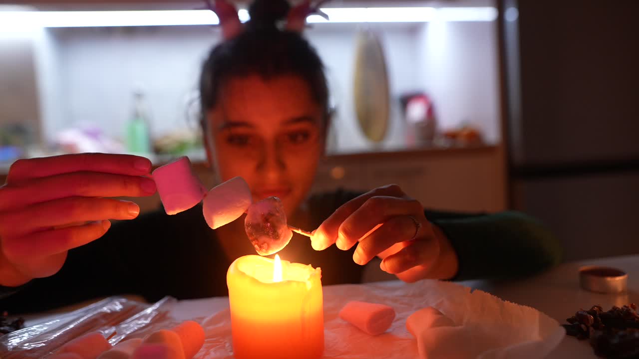 Woman roasting marshmallows over a candle